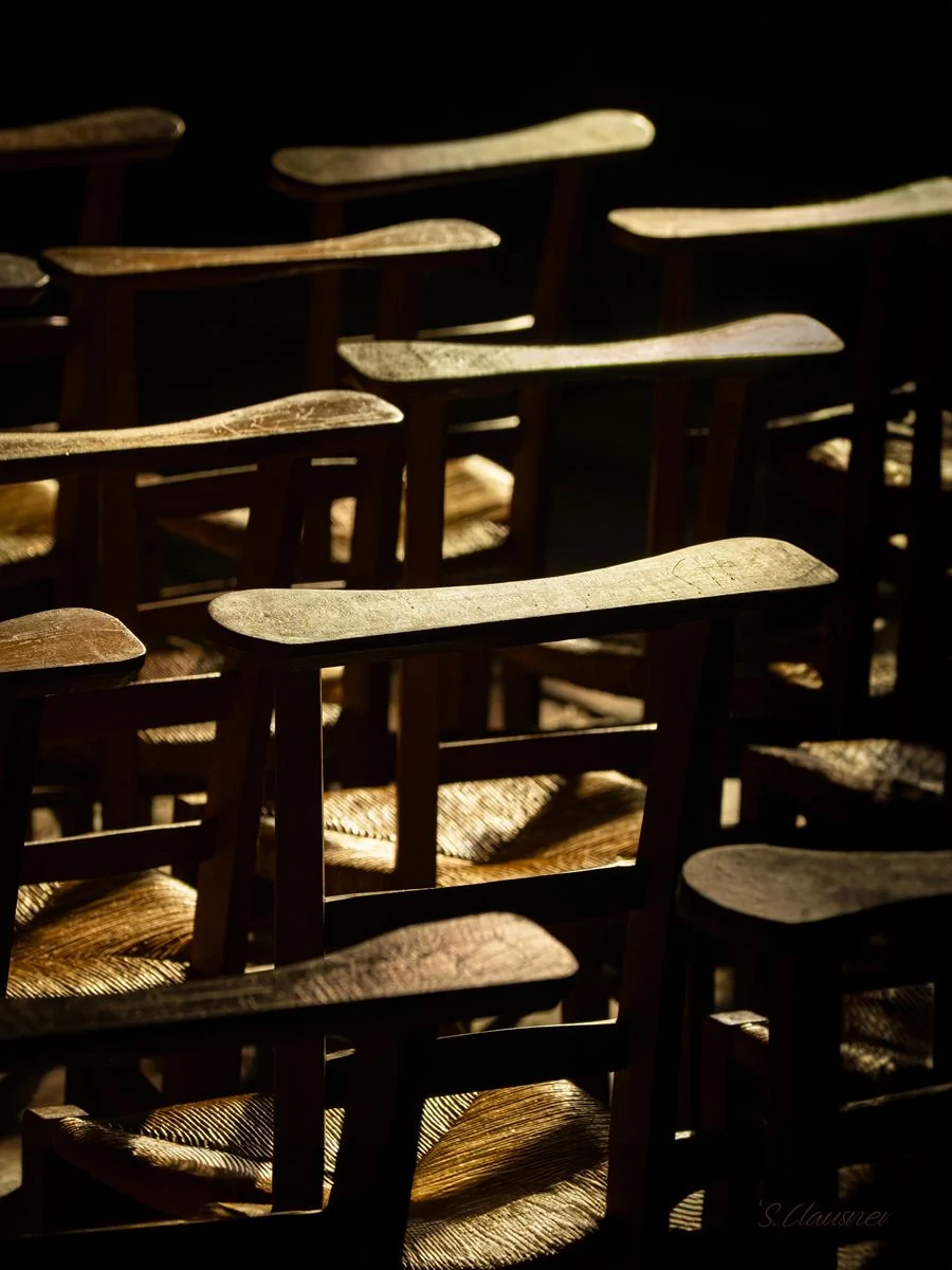 Dossiers de chaises éclairés dans une église sombre
