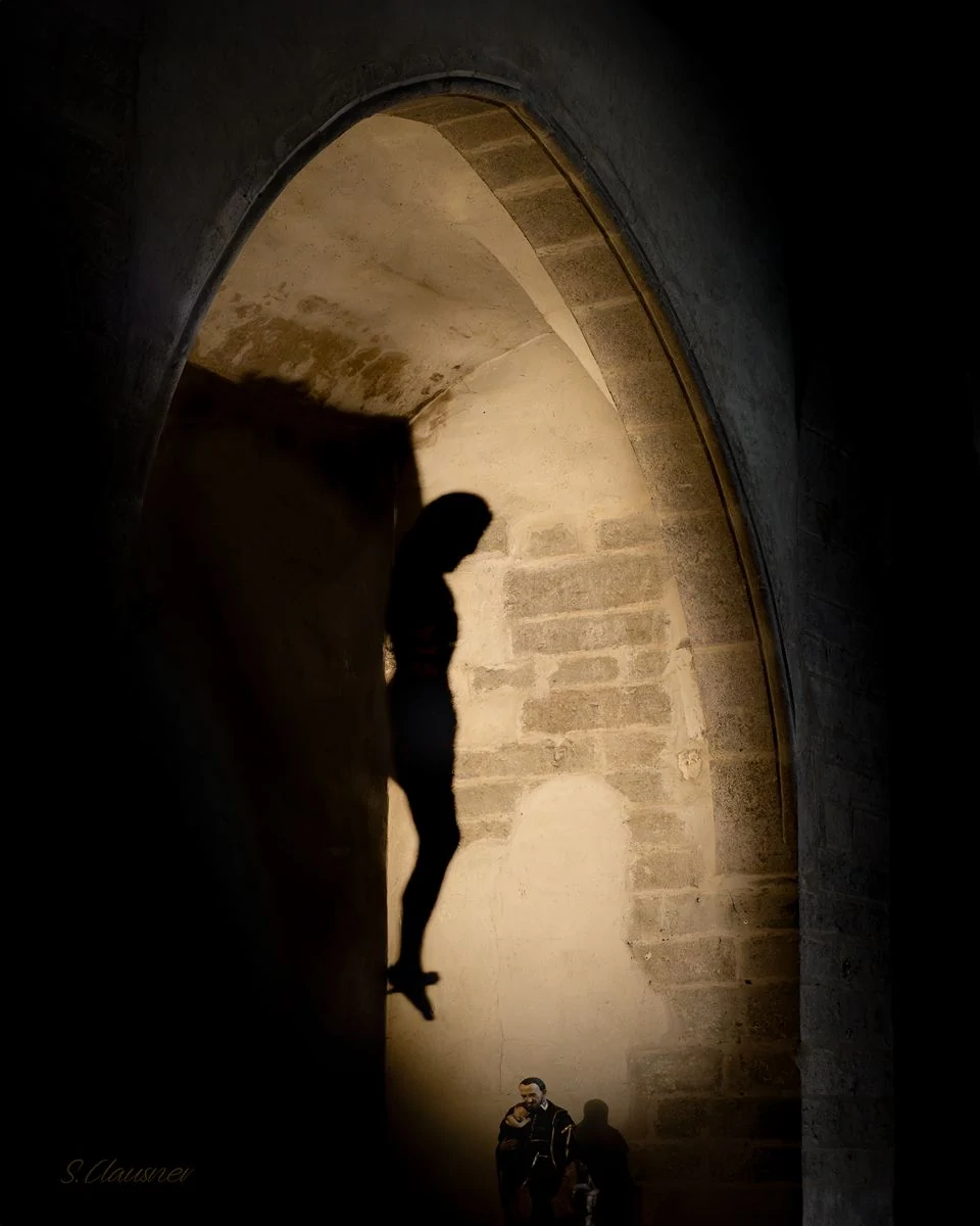 Christ en croix silhouetté sous une arche de pierre