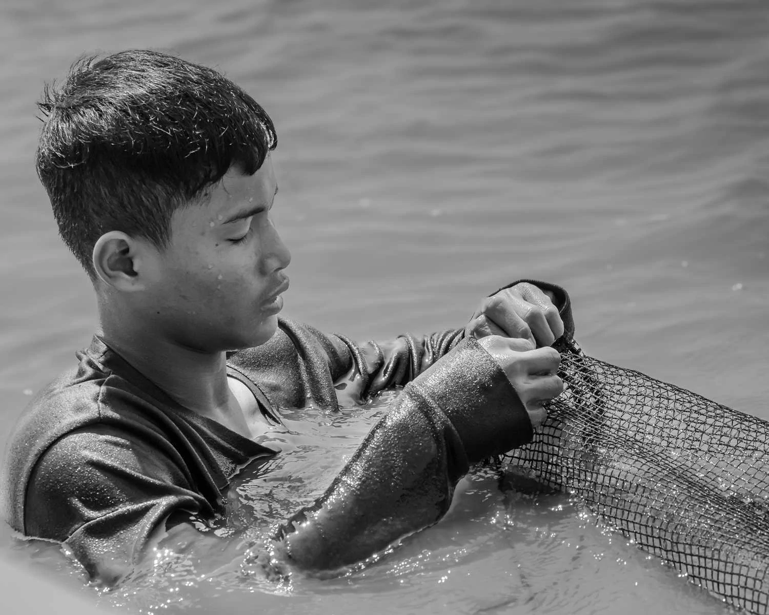 Jeune pêcheur travaillant son filet dans l’eau